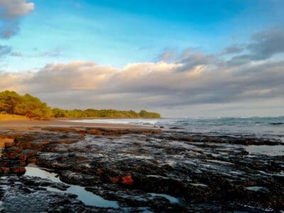 Rocky shoreline and beach at Marbella at sunset under a cloudy sky