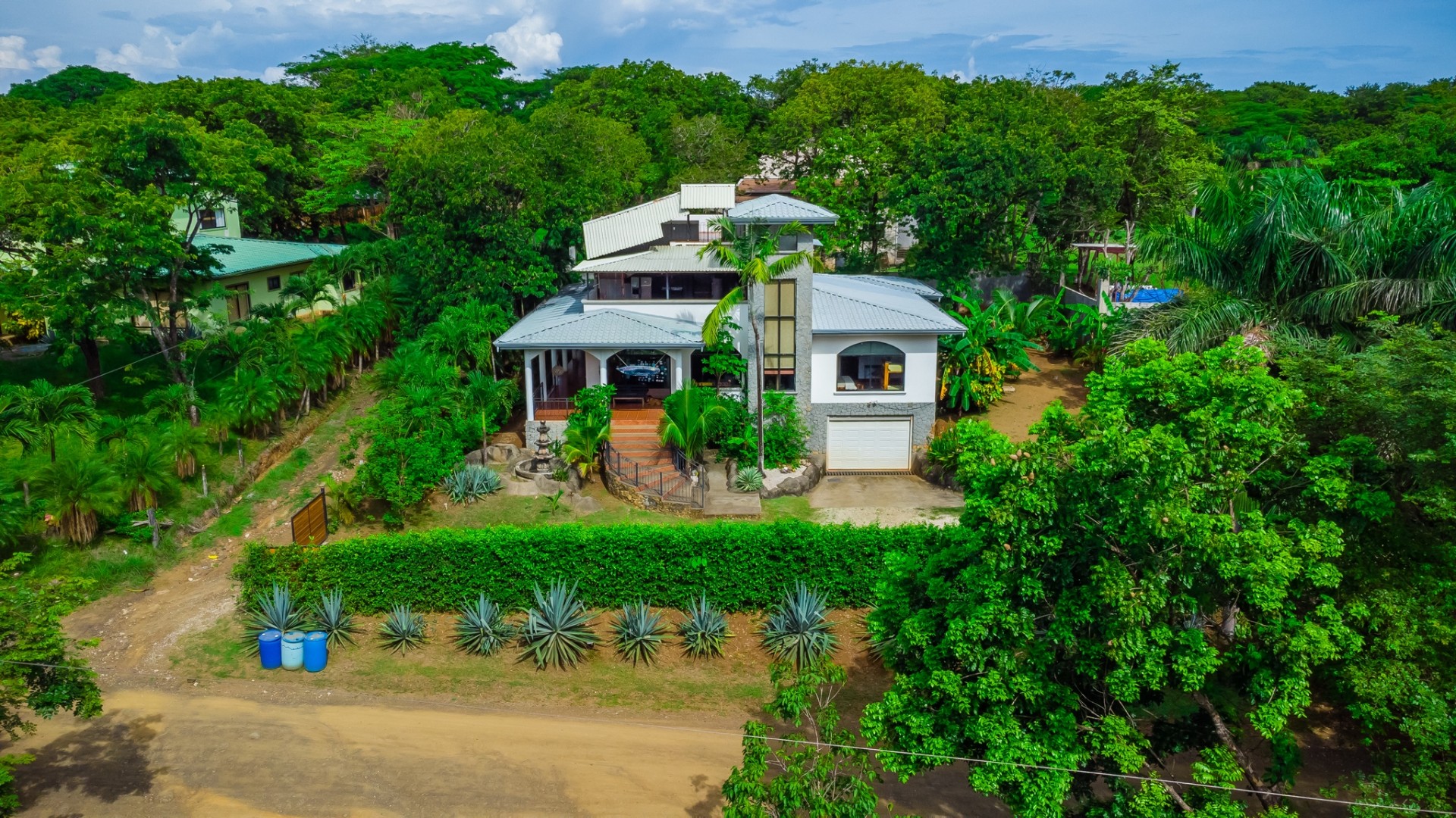 Aerial view of a white two-story home surrounded by tropical gardens in Marbella