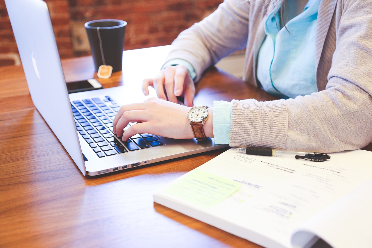 Person working on a laptop with notes and coffee