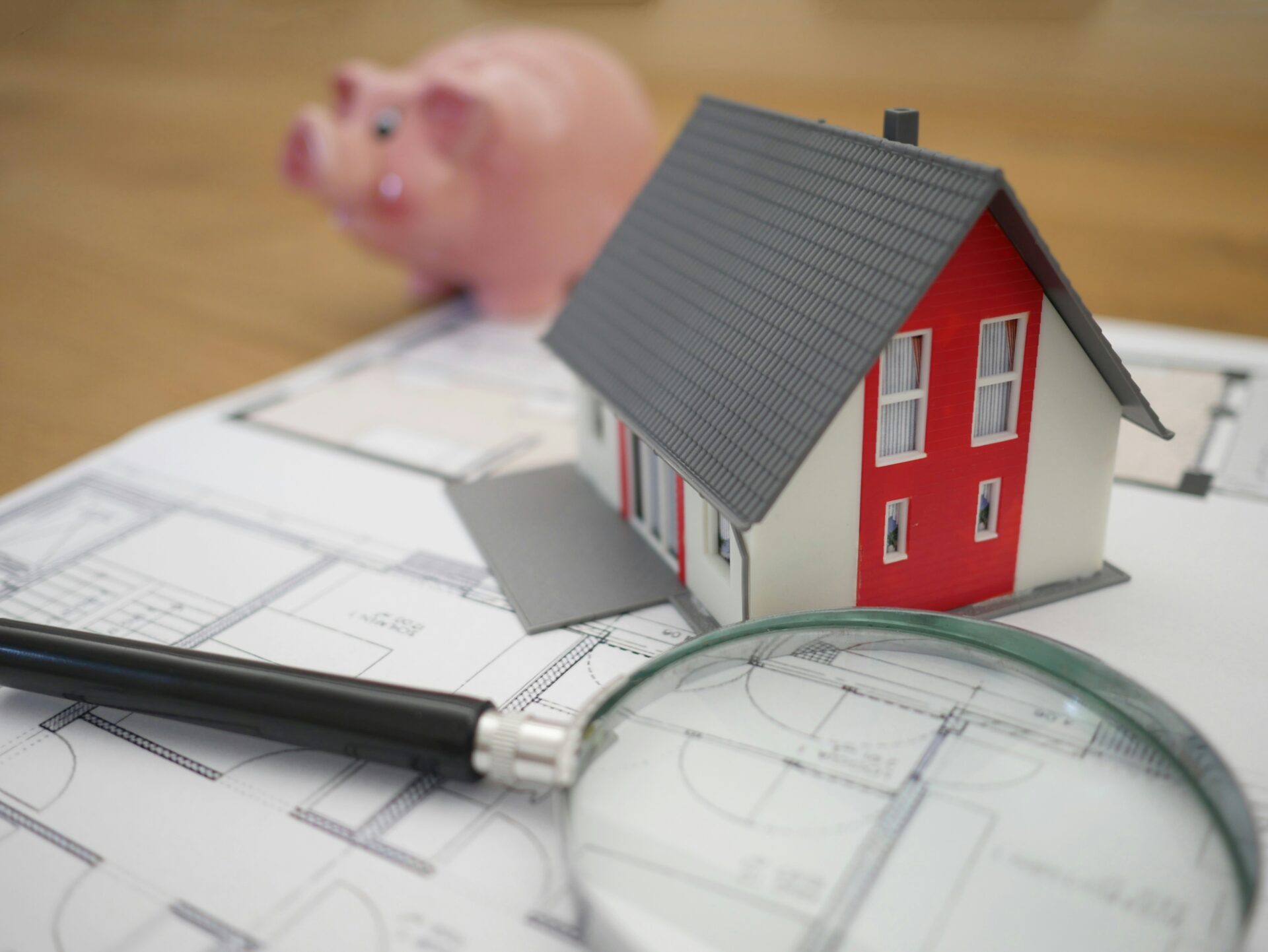 Model house and magnifying glass on floor plans during a home search